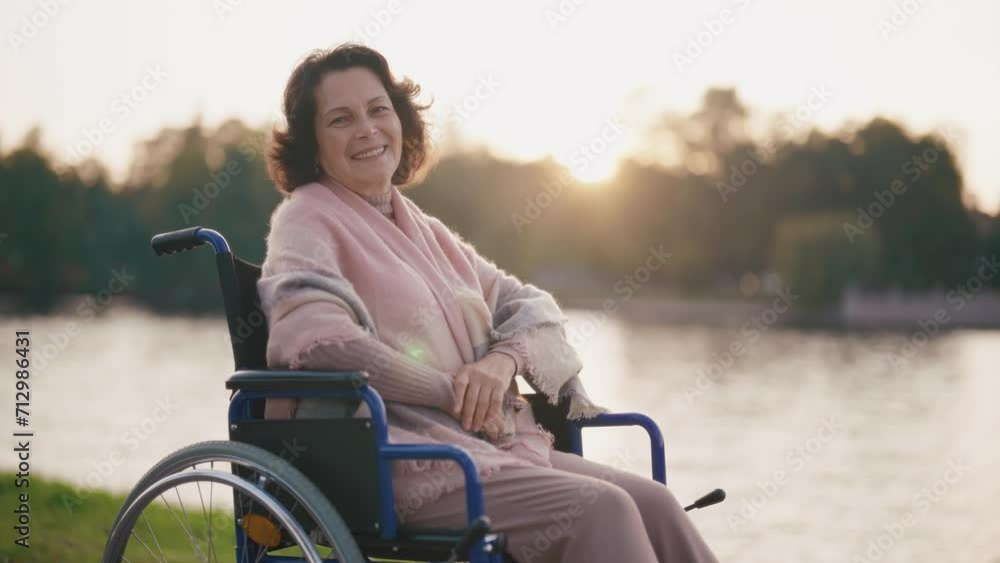 Senior woman in wheelchair smiling on nature. Happy elderly mature grandmother enjoy a walk at sunset look camera. Happiness old, living with legs paralysis, special needs pensioner care concept. Senior woman in wheelchair smiling on nature. Happy elderly mature grandmother enjoy a walk at sunset look camera. Happiness old, living with legs paralysis, special needs pensioner care concept.