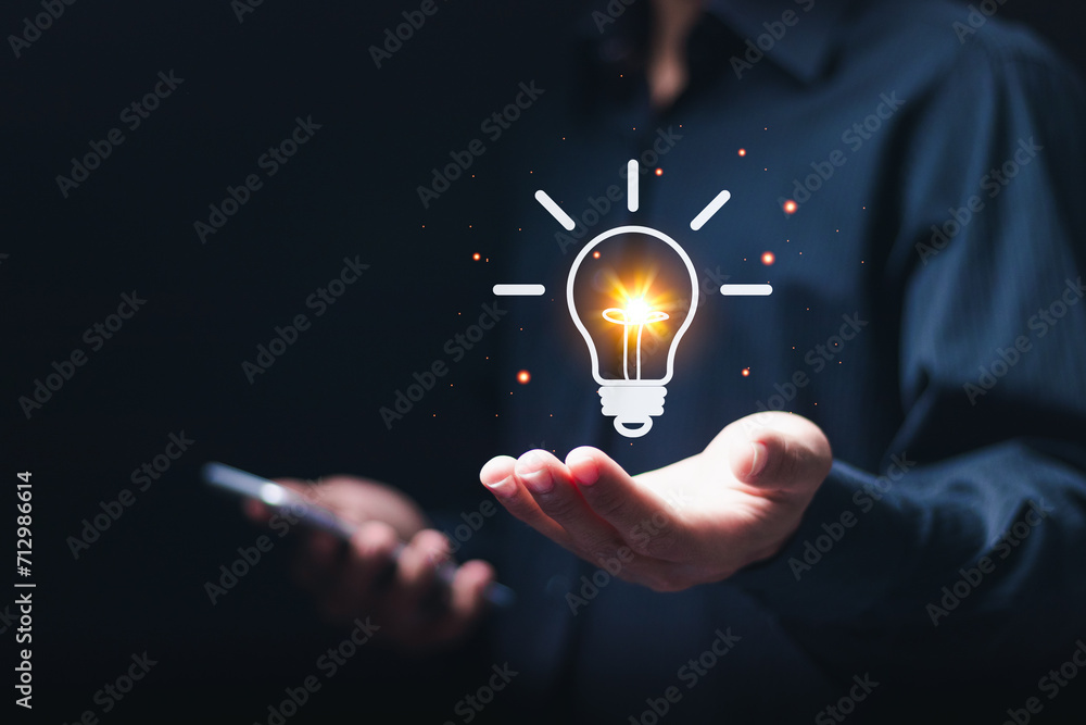 Business creativity and inspiration concept. businessman holding virtual light bulb icon for motivation for success and thinking of ideas. - obrazy, fototapety, plakaty 