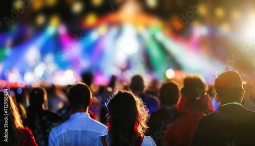 Personnes devant un concert de festival de musique avec gens devant une scène éclairée, la foule danse et écoute le spectacle. Espace flou pour titre ou texte.
