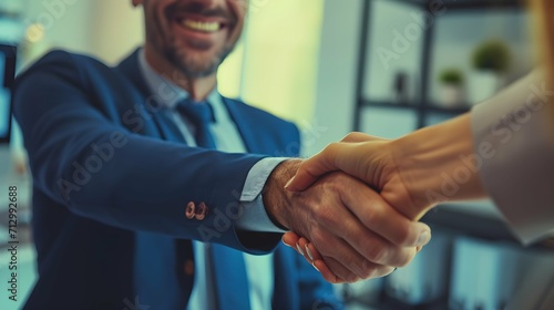 Portrait of cheerful young manager handshake with new employee. Business partnership meeting in office. Close up of handshake in the office. Mature businessman shake hands with a younger colleague photo