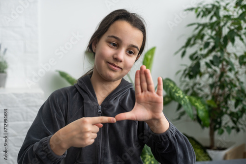 Cute deaf mute girl using sign language on light background photo