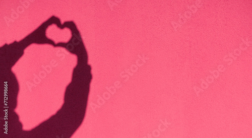 Shadow hands in the shape of a heart on the background of a colored sunny wall. Love  emotions  life  support concept