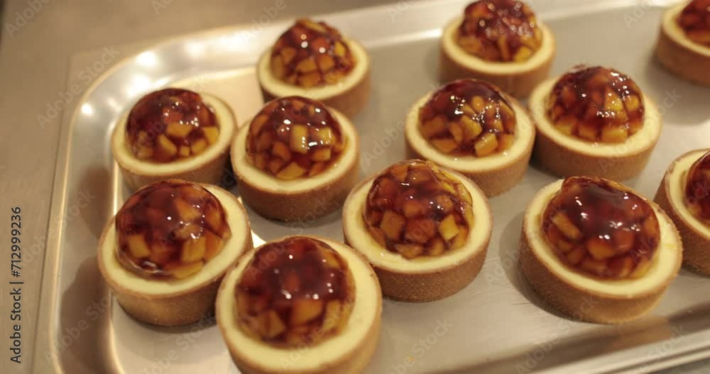 Tartlets on the table of a professional confectioner are decorated with apple-jelly filling. Tartlets on the table of a professional confectioner are decorated with apple-jelly filling.