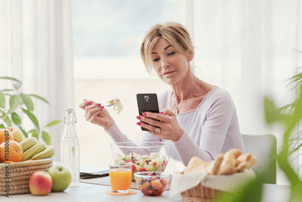 Woman eating and chatting with her smartphone