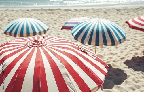 red white and blue striped umbrellas on a sandy beach © olegganko