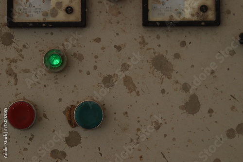 A water tank motor switch button box or panel with paint stains and green indicator light, dirty photo