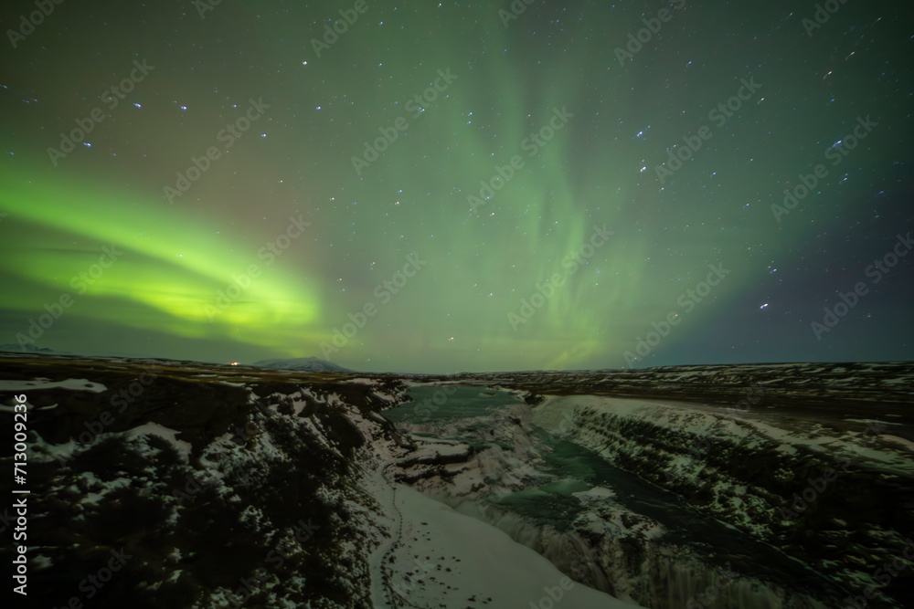 Northern lights in Gullfoss area in winter with ice in Iceland
