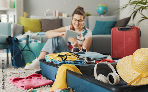 Happy woman packing for a trip and connecting online