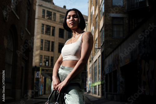 Portrait of young asian female looking at camera in a narrow street of London. photo