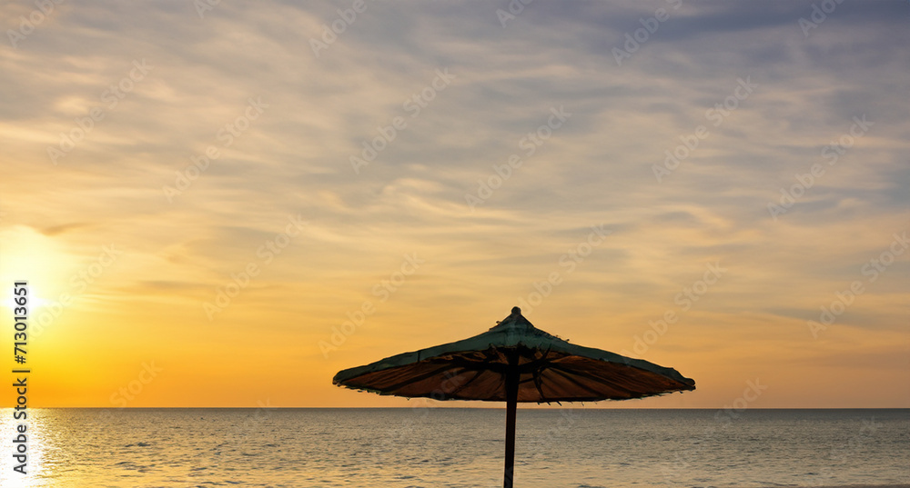 an umbrella on a beach at sunset