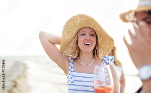 Happy adult woman with wine resting on beach with friends