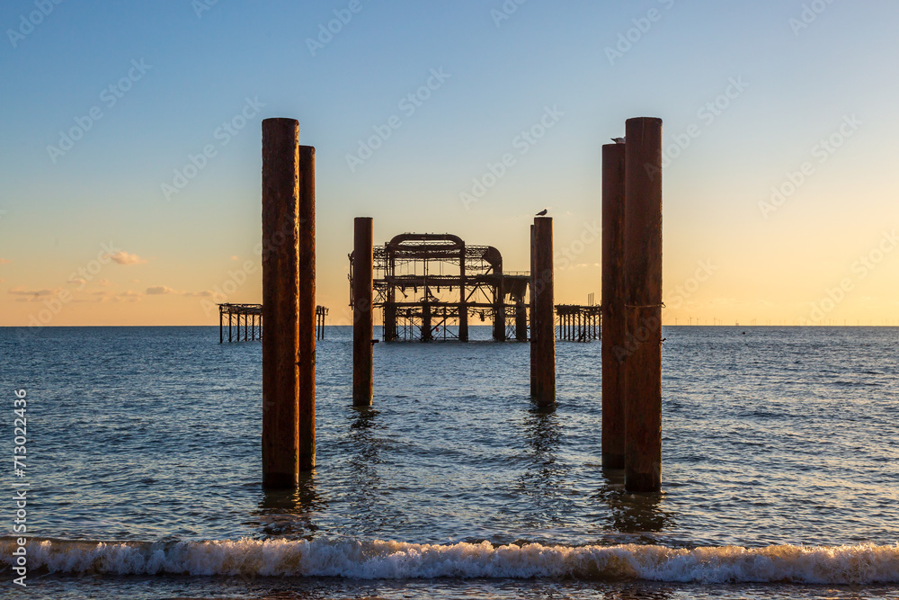 Looking out over the sea and the ruins of the West Pier at sunset, in Brighton, Sussex