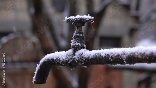Faucet frozen with ice, snow, frost in winter as a symbol of climate change and extreme weather