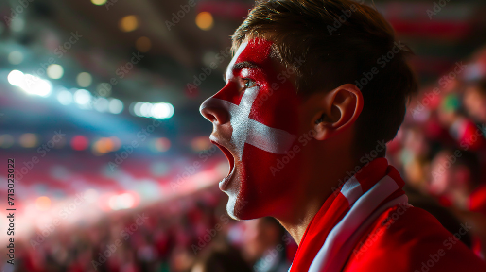 Passionate Danish soccer fan cheering in stadium with red and white Danish national face paint.
