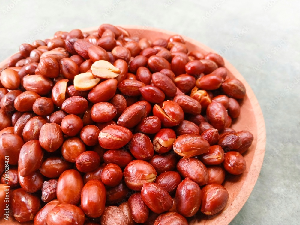 Obraz premium Fried peanuts on wooden plate on gray background. Deep fried peanuts on plate. Half shot. Close up
