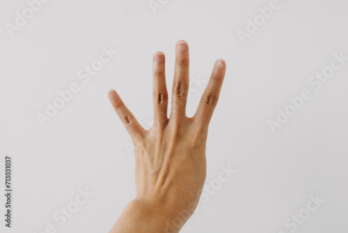 Photo of woman's back hand showing numbers four, counting fingers gesture, isolated on white background wall. photo