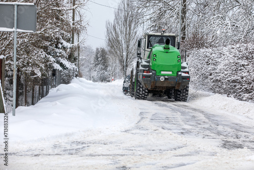 Tractor clears snow on road after heavy snowfall, road maintenance in winter season
