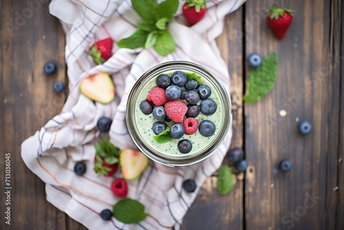 overhead shot: blended spinach berry smoothie in a mason jar, surrounded by raw ingredients