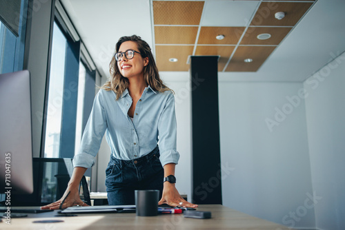 Female professional standing at her desk in an office photo
