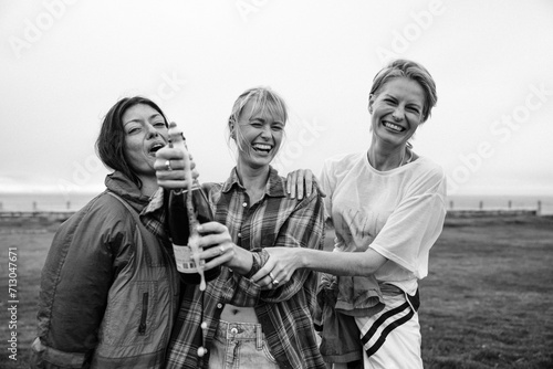 Girlfriends popping a champagne bottle in celebration photo