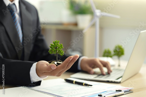Businessman holding coin with a tree growing on money coin stack. Investment Ideas and Green Business Growth. Finance sustainable development. Alternative sources of energy. Eco business investment photo