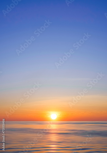 Idyllic natural sunrise sky background over sea in the morning with beautiful golden sunlight reflection on flowing water surface in vertical frame © Prapat