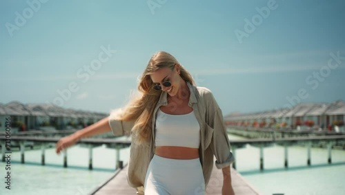 Wallpaper Mural Happy Blonde woman walking on a Maldives luxury resort island with a row of wooden sea bungalows and blue sky in the background Torontodigital.ca