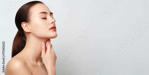 Cropped shot of a young woman touching her him with her hands, massaging her face on a light background. Rejuvenation, facelift, face fitness. Exercises for double chin, pelican neck