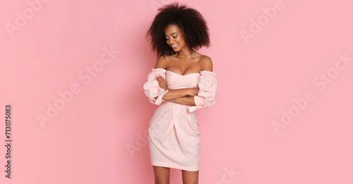Beautiful afro american woman in a pink dress on a pink background. photo