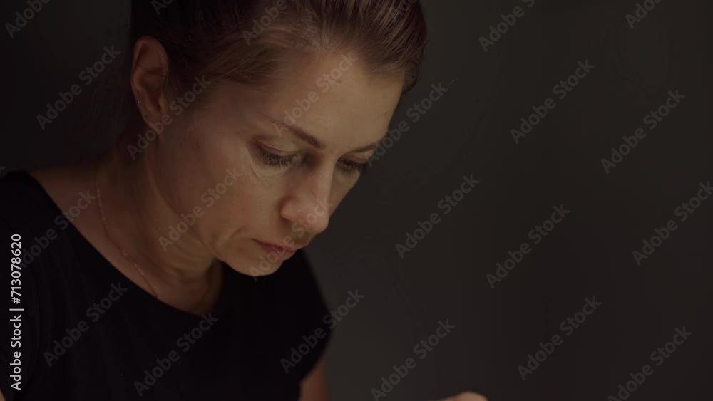 Close-up of face of an attractive woman looking down and doing something in dark room Close-up of face of an attractive woman looking down and doing something in dark room