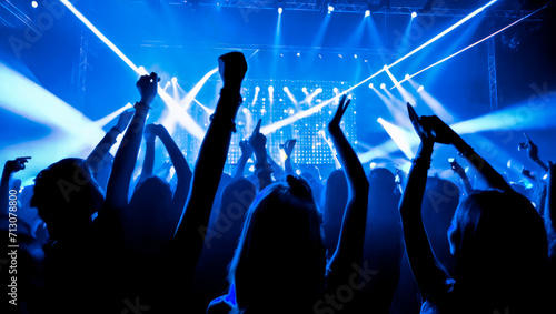 crowd dancing with neon blue lasers. People dancing at party with hands up. Silhouette crowd rejoices under bright stage lights at music festival. nightlife, clubs, concerts and festivals