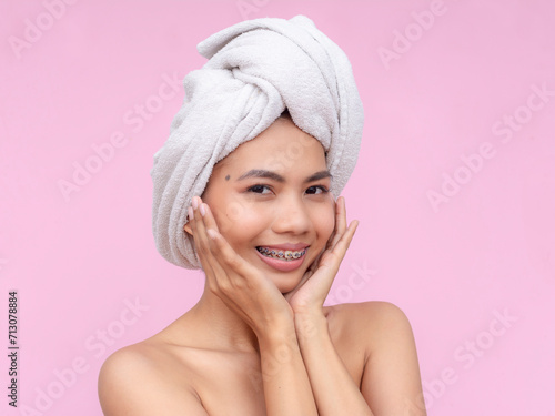 Portrait of a cheerful young Asian woman with braces and a head towel, radiating natural beauty.