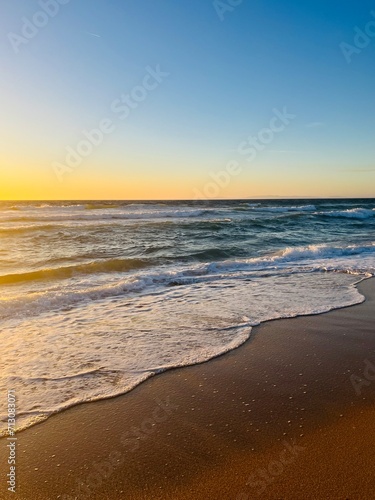 Warm colors of the seascape  sand sea coastline  sea waves on the sand  clear blue sky  no people  empty beach