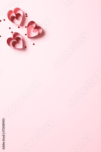 Happy Valentines Day concept. Vertical pink background with red paper cut hearts and confetti. Minimal style.
