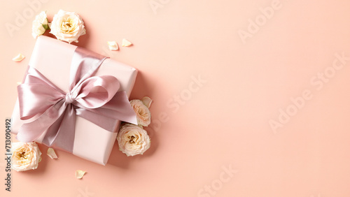 Gift box with ribbon bow and roses buds on pastel beige background. Happy Valentines day, Mothers day, International womens day concept. © photoguns