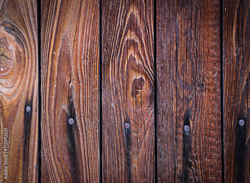 Deski drewniane w brązowym kolorze przybite gwoździami z widocznymi sękami i słojami ułożone pionowo - tło, tapeta, tekstura