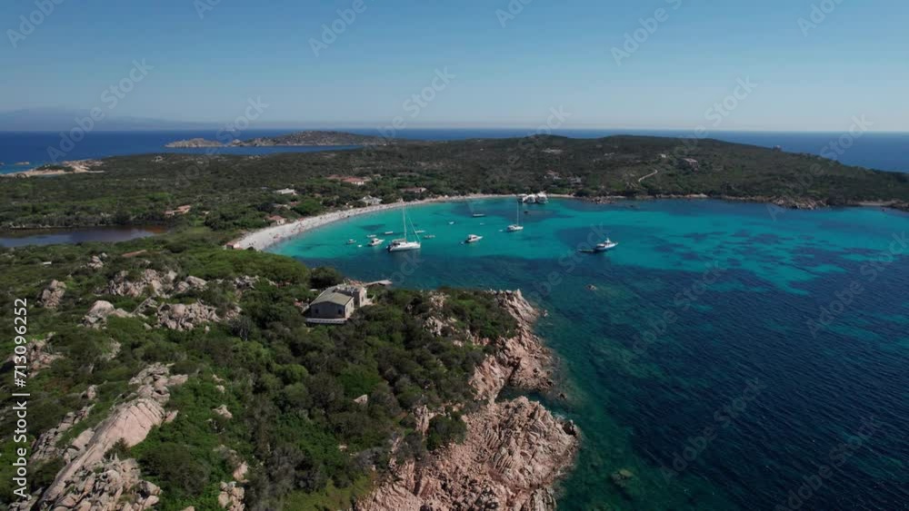 aerial sideways shot panoramic view of protected area of Sardinia,Italy with boats anchored off coast and people enjoying sun during holidays aerial sideways shot panoramic view of protected area of Sardinia,Italy with boats anchored off coast and people enjoying sun during holidays