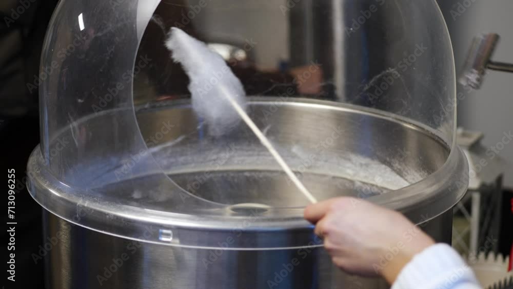 Kind woman creates a fluffy cloud of cotton candy for a delighted child Kind woman creates a fluffy cloud of cotton candy for a delighted child