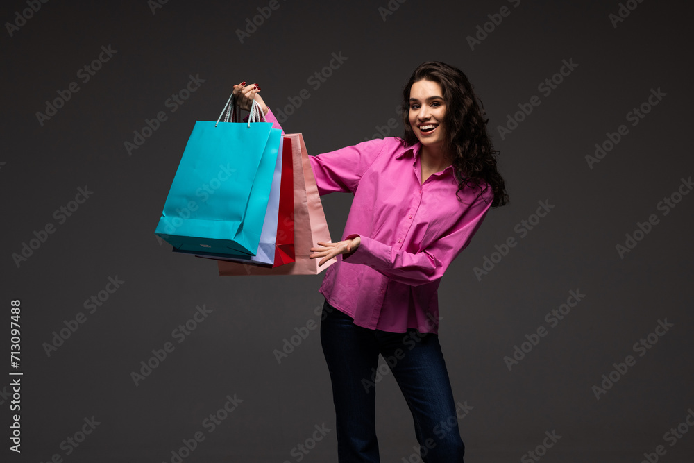 Black friday sale concept. Shopping woman holding grey bag isolated on dark background in holiday