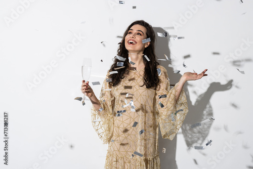 Young stylish woman on white background drinking champagne, celebrating new year, glass, having fun