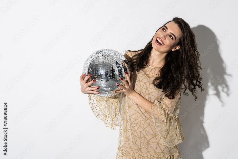 Naklejka premium Happy young woman wearing dress smiling is holding disco ball. Party concept