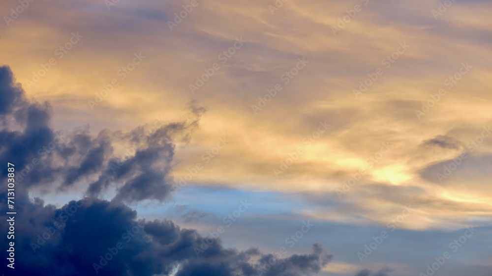 Clouds at sunset. The sky is painted with bright colors by the rays of the setting sun. The rays of the setting sun pass through the clouds.