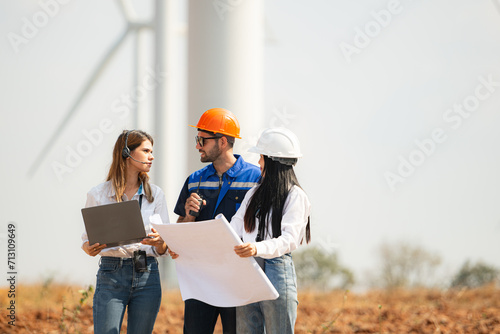 Engineer and Architect working on construction site with wind turbine background.