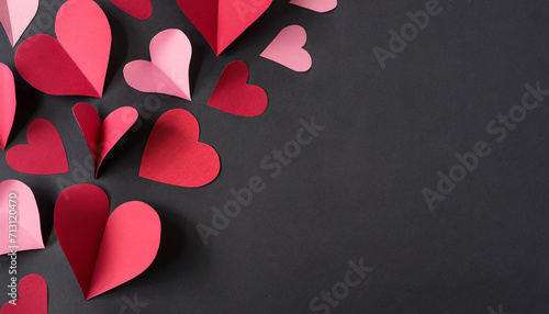 Red and pink cut out paper hearts on black paper with copy space photo