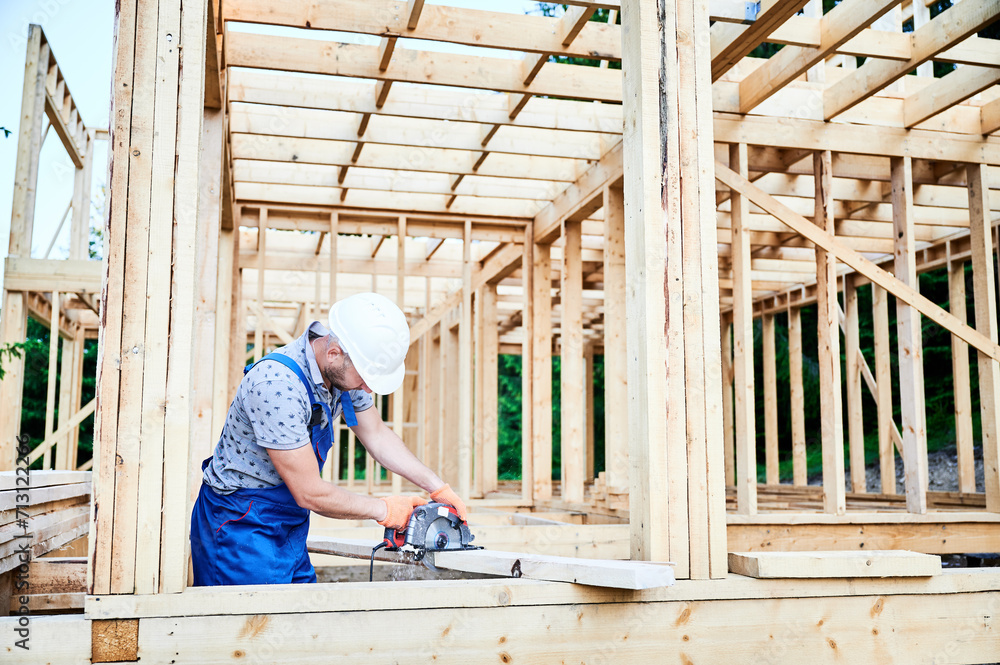 Carpenter using circular saw for cutting wooden plank. Man worker building wooden frame house. The idea behind modern ecological construction. Carpenter using circular saw for cutting wooden plank. Man worker building wooden frame house. The idea behind modern ecological construction.