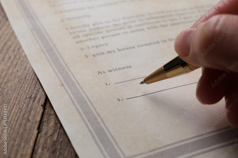 Woman signing Last Will and Testament at wooden table, closeup Woman signing Last Will and Testament at wooden table, closeup