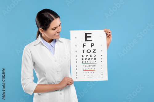 Ophthalmologist with vision test chart on light blue background