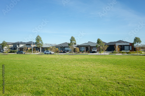 Large open space with green grass lawn with some residential houses in the background. A public park in a suburban neighbourhood with modern Australian homes. Copy space for your design. photo