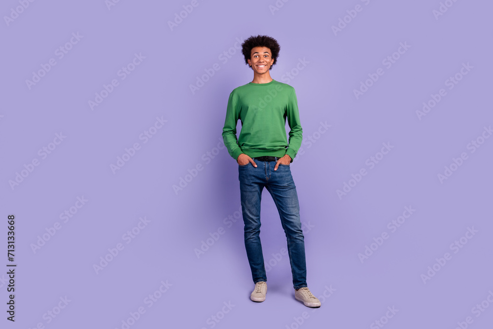 Full length photo of good mood positive man dressed green sweater smiling walking empty space isolated violet color background Full length photo of good mood positive man dressed green sweater smiling walking empty space isolated violet color background