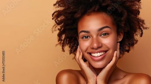Happy young adult African American woman beauty female model, pretty 20s Black lady with curly hair beautiful face advertising skin care products isolated at beige background. Aesthetic authentic shot